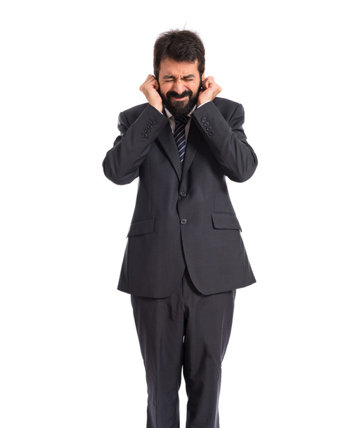 Businessman covering his ears over white background - Fotoğraf, Görsel