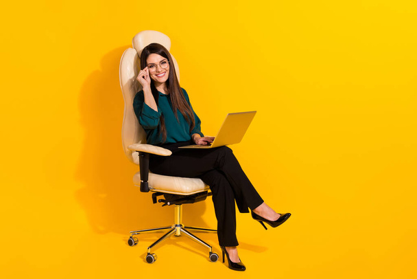 Full length profile side photo of young cheerful lady use laptop manager boss sit stool isolated over yellow color background - Zdjęcie, obraz
