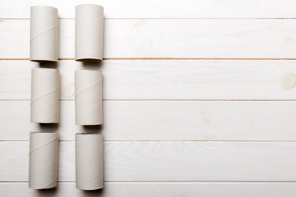 Flache Lagekomposition mit leeren Toilettenpapierrollen und Platz für Text auf farbigem Hintergrund. Recyclingpapierröhre mit Metallstecker aus Kraftpapier oder Karton. - Foto, Bild