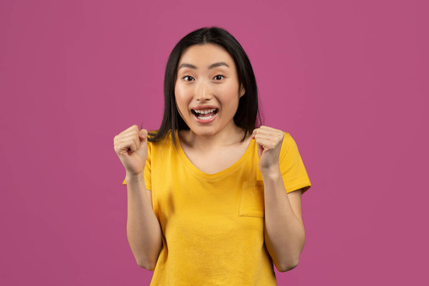 Ja, Leistungskonzept. Überglückliche asiatische Frau jubelt und schreit und feiert Sieg über violetten Hintergrund - Foto, Bild