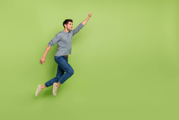 Full body photo of cheerful cool positive super male flying to save the world isolated on green color background - Foto, imagen