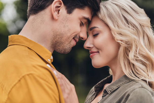 Cropped profile side view portrait of attractive sweet cheerful sweet couple enjoying cuddling on fresh air outdoors - Foto, immagini