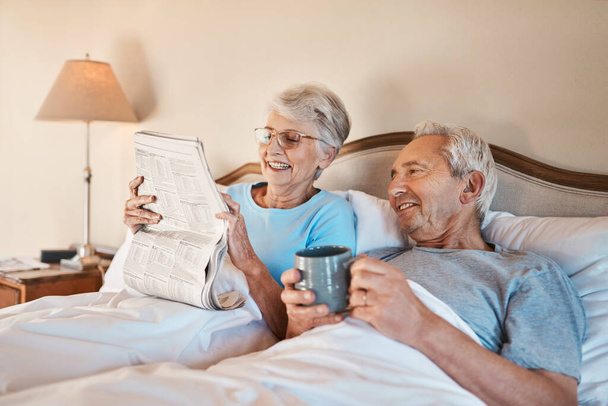 Ποια λέξη νομίζεις ότι πάει εδώ; Τραβηγμένη φωτογραφία μιας ηλικιωμένης γυναίκας να διαβάζει εφημερίδα στο κρεβάτι ενώ ο άντρας της πίνει καφέ.. - Φωτογραφία, εικόνα