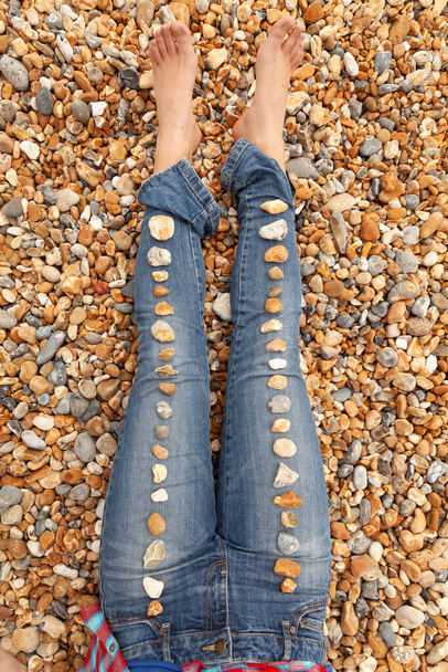 As pernas de uma jovem, com os pés descalços, cobertas por linhas de seixos, na praia de Brighton, sul da Inglaterra, Reino Unido - Foto, Imagem
