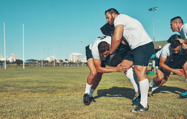 Mastering the basics of safe and effective tackling. Shot of rugby players training with tackle bags on the field. - Foto, Imagen