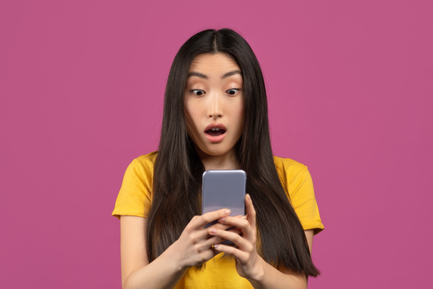 Şaşırmış Koreli kadının portresi akıllı telefon ekranına heyecanla bakıyor, cep telefonu teklifine duygusal tepki veriyor. - Fotoğraf, Görsel