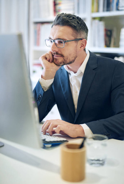 He has a keen eye for detail. Shot of a mature businessman working at his computer in an office. - Φωτογραφία, εικόνα