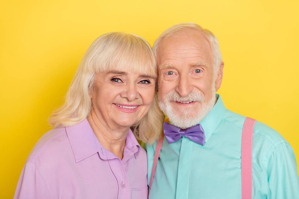 Portrait of two attractive cheery grey-haired spouses bonding romance isolated over bright yellow color background - Foto, Bild