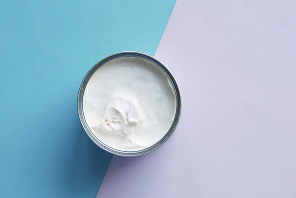 vista superior de la crema de leche en un recipiente sobre fondo azul, - Foto, imagen