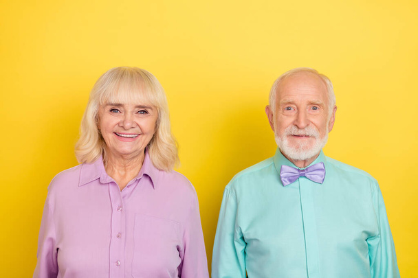 Portrait of two attractive cheerful grey-haired people wearing festal shirt isolated over bright yellow color background - Foto, Bild