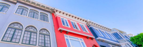 Gebäude in einem niedrigen Winkel Ansicht mit kunstvollen Zierleisten in San Francisco Bay Area in Kalifornien. Es gibt ein rotes Gebäude in der Mitte des grauen Gebäudes auf der linken und ein blaues Gebäude auf der rechten Seite. - Foto, Bild