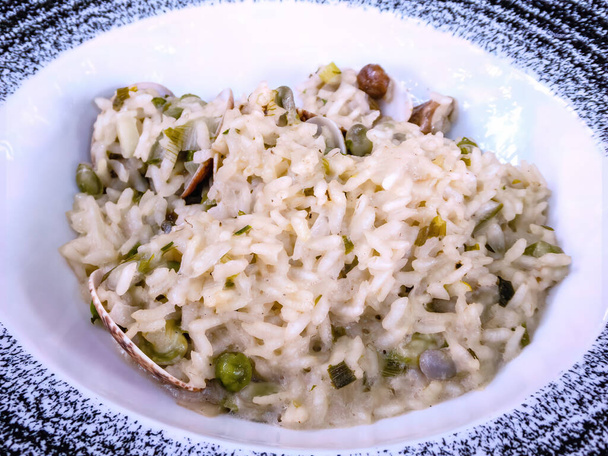 pyszne risotto z owoców morza z małżami, kalmary i świeże pomidory wiśniowe - gotowany ryż na białym talerzu - risotto ai frutti di mare - Zdjęcie, obraz