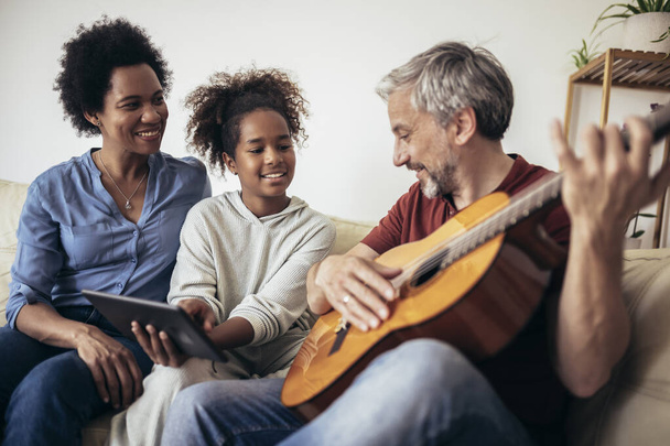 Uomo che canta e suona la chitarra per sua figlia e sua moglie. - Foto, immagini