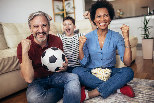 Возбужденные фанаты семейного футбола вместе смотрят спортивное телевидение, празднующее гол - Фото, изображение
