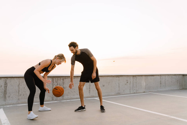 Young man and woman working out with ball together on parking outdoors - Foto, Bild