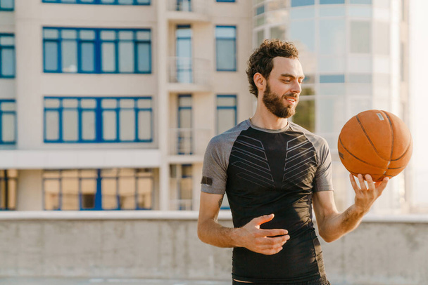 Young man smiling while workout with ball on parking outdoors - Foto, Imagen