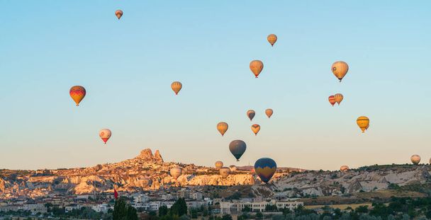 Set of colorful balloons flying over Goreme city in Cappadocia, during sunset on a clear summer day, copy space - Foto, imagen