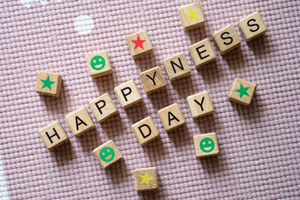 Word sHappiness Day steht in Holzwürfeln zwischen Sternen und lächelt in Großaufnahme - Foto, Bild