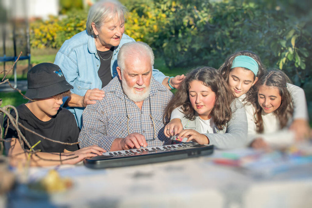 Grandfather playing outdoor with his grandchildren with music instruments - Photo, Image