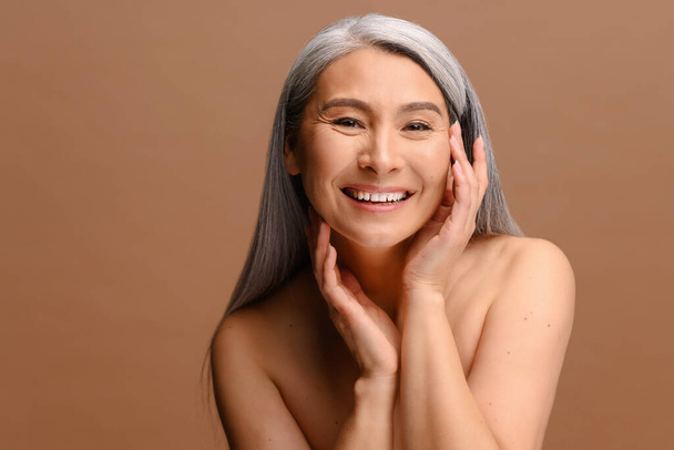 Enchanting topless middle aged Asian woman looks at the camera and laughing happily - Photo, Image