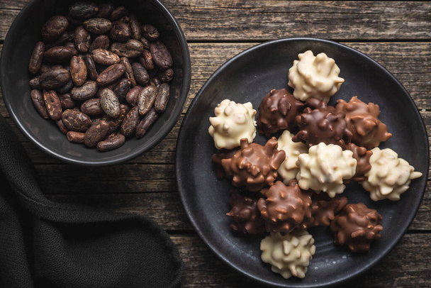 Chocolate truffles. Sweer pralines on plate on a wooden table. Top view. - Fotó, kép
