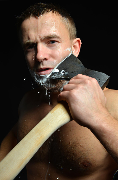 Bearded young man shaving with big axe foam and water splashes  - Фото, зображення