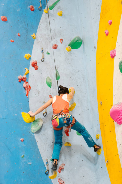 Young Woman rock climbing indoors. - Фото, зображення