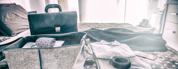 Packing suitcase for business travel. Clothes and briefcase on the bed - Foto, afbeelding