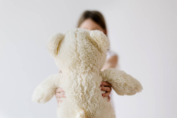 rearview of white teddy bear - unrecognizable little girl holding her stuffed plush for sleeping - Foto, imagen