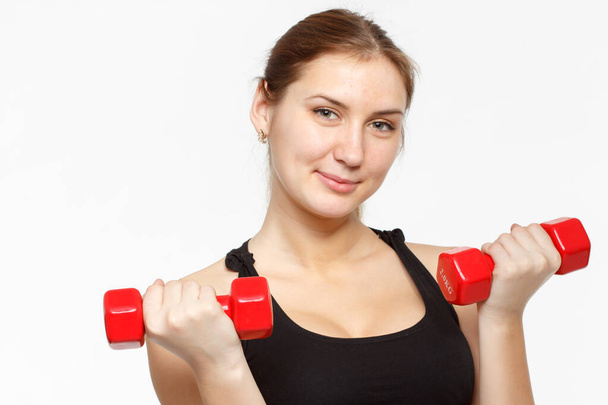Modèle de fitness féminin excercisant en studio avec des poids dunbell et faisant une routine au sol d'étirements et d'ascenseurs sur un mat
. - Photo, image