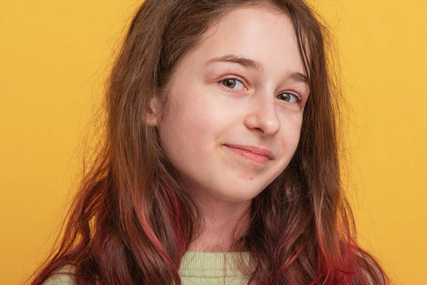 Το κορίτσι είναι σε θετική διάθεση. Πορτρέτο μιας έφηβης σε κίτρινο φόντο. - Φωτογραφία, εικόνα