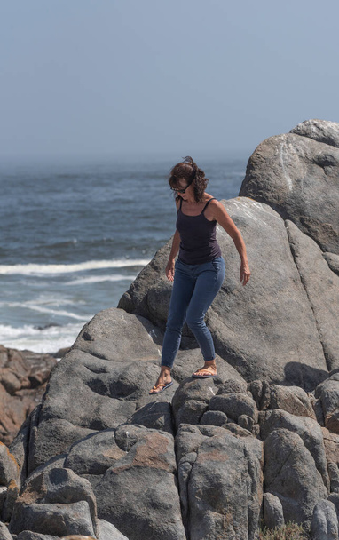 West Coast, South Africa. 2022. Woman climbing over rocks at a seaside location on the West Coast, South Africa - Photo, image