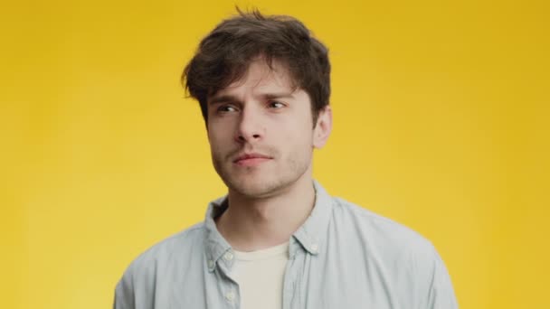 Young guy thinking and having great idea, pointing finger up with open mouth, expressing eureka, yellow background - Footage, Video
