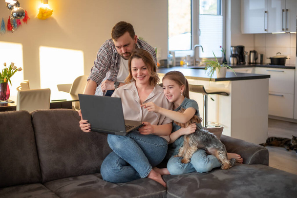 Ευτυχισμένη οικογένεια νέοι χρησιμοποιούν φορητό υπολογιστή μαζί στο σπίτι - Φωτογραφία, εικόνα