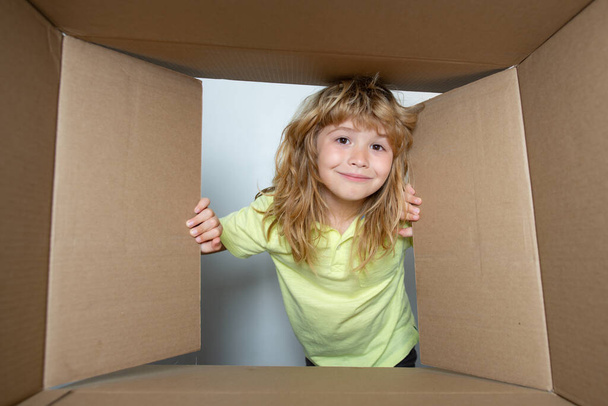 Excited child boy looking into the box, shipping cardboard box. Parcels and delivery. - Fotografie, Obrázek