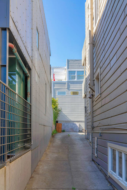 カリフォルニア州サンフランシスコの住宅建築物の真ん中で最も狭いコンクリート舗装。外壁の異なる両側に2つの建物があり、奥には建物の景色が見えます。. - 写真・画像