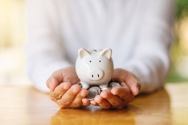 Nahaufnahme einer Frau, die Sparschwein und Münzen hält, um Geld zu sparen - Foto, Bild