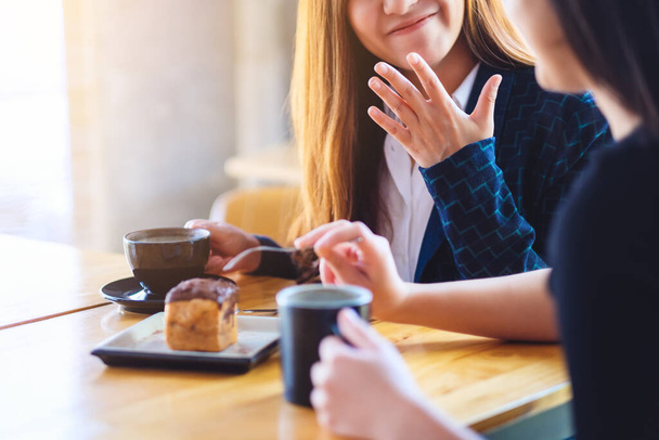 Zbliżenie obraz kobiet cieszył jedzenia deseru i picia kawy razem w kawiarni - Zdjęcie, obraz