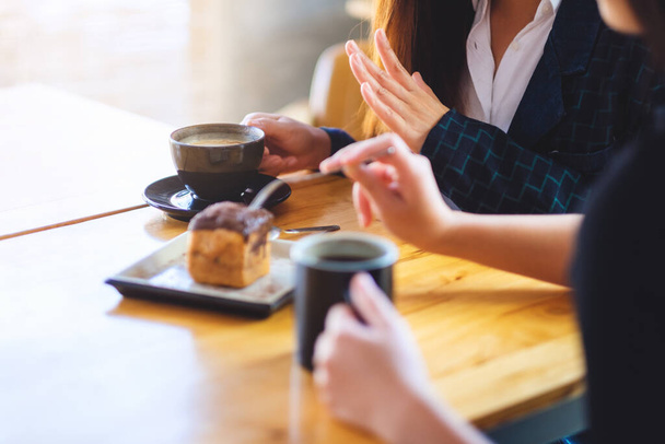 Closeup image of women enjoyed eating dessert and drinking coffee together in cafe - Photo, image