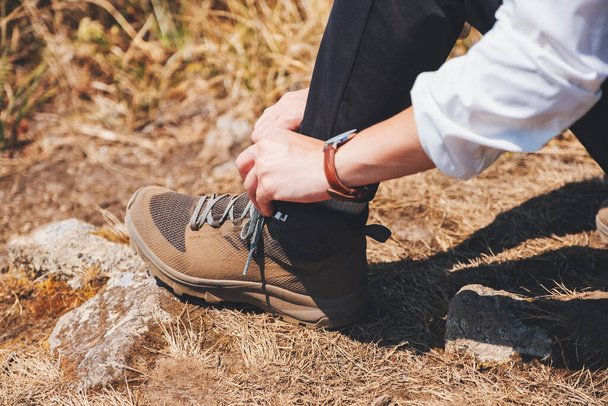 Imagen de cerca de una mujer excursionista atando cordones de zapatos y preparándose para el trekking en la cima de la montaña - Foto, imagen