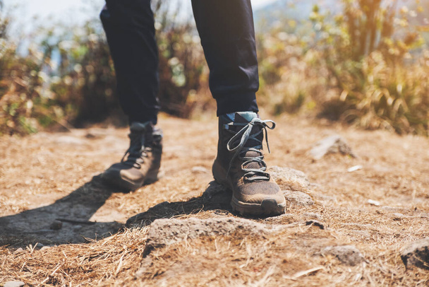 Closeup image of a woman hiking with trekking boots on the top of mountain - Photo, Image