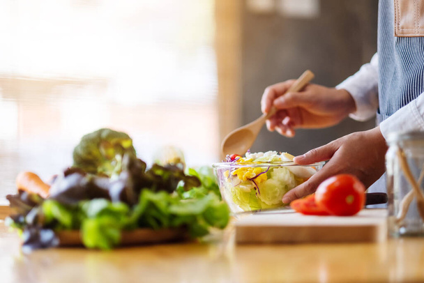 Imagem de perto de uma cozinheira chef fêmea e segurando uma tigela de salada de legumes misturados frescos na cozinha - Foto, Imagem
