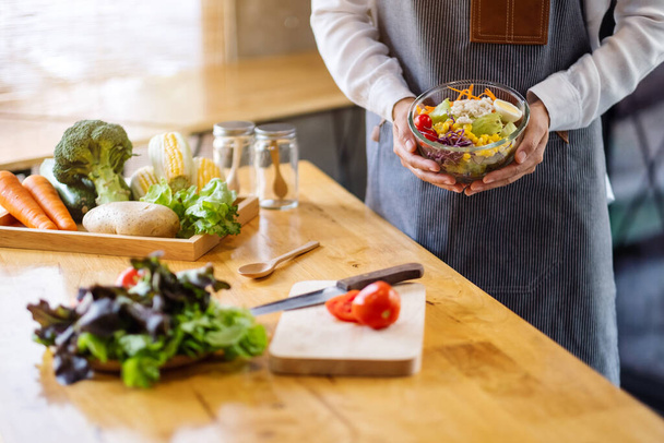 Крупный план приготовления пищи женского шеф-повара с миской салата из свежих овощей на кухне - Фото, изображение