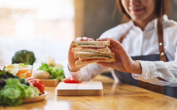 Immagine ravvicinata di una cuoca che cucina e mostra un panino integrale in cucina - Foto, immagini