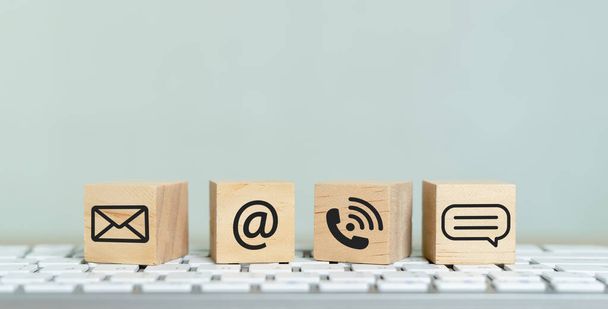 Concept of contact us. wooden cube blocks with contact icons on computer keyboard. symbol of connection, email telephone and dialog box. Technology social network. - 写真・画像