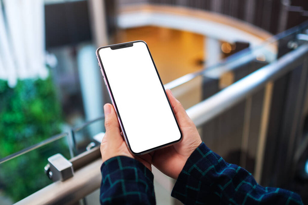 Mockup image of a woman holding mobile phone with blank white screen indoors - Fotografie, Obrázek