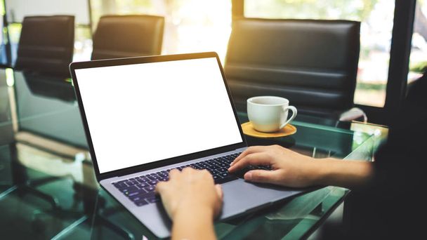Mockup image of a businesswoman using and typing on laptop computer with blank white desktop screen in the office , coffee cup on the table - 写真・画像
