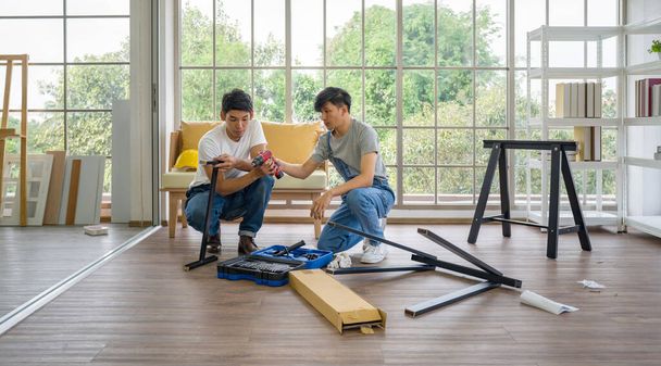 Dwóch azjatyckich stolarzy instalujących drewnianą ławkę w nowym domu. Usługi remontowe domu. Poranna atmosfera pracy w salonie. - Zdjęcie, obraz