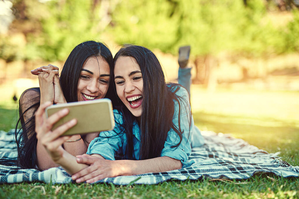 Täytyy ottaa kesäajan selfieitä. Kaksi nuorta ystävää ottamassa selfietä puistossa.. - Valokuva, kuva