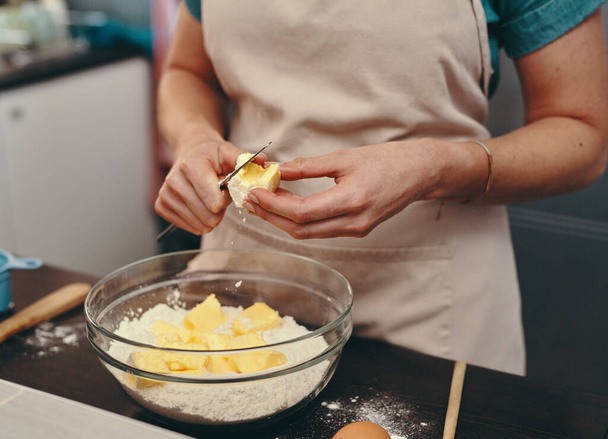 Assar não é apenas um hobby, é uma paixão. Tiro cortado de uma mulher irreconhecível cortando blocos de manteiga enquanto assava dentro de sua cozinha em casa. - Foto, Imagem